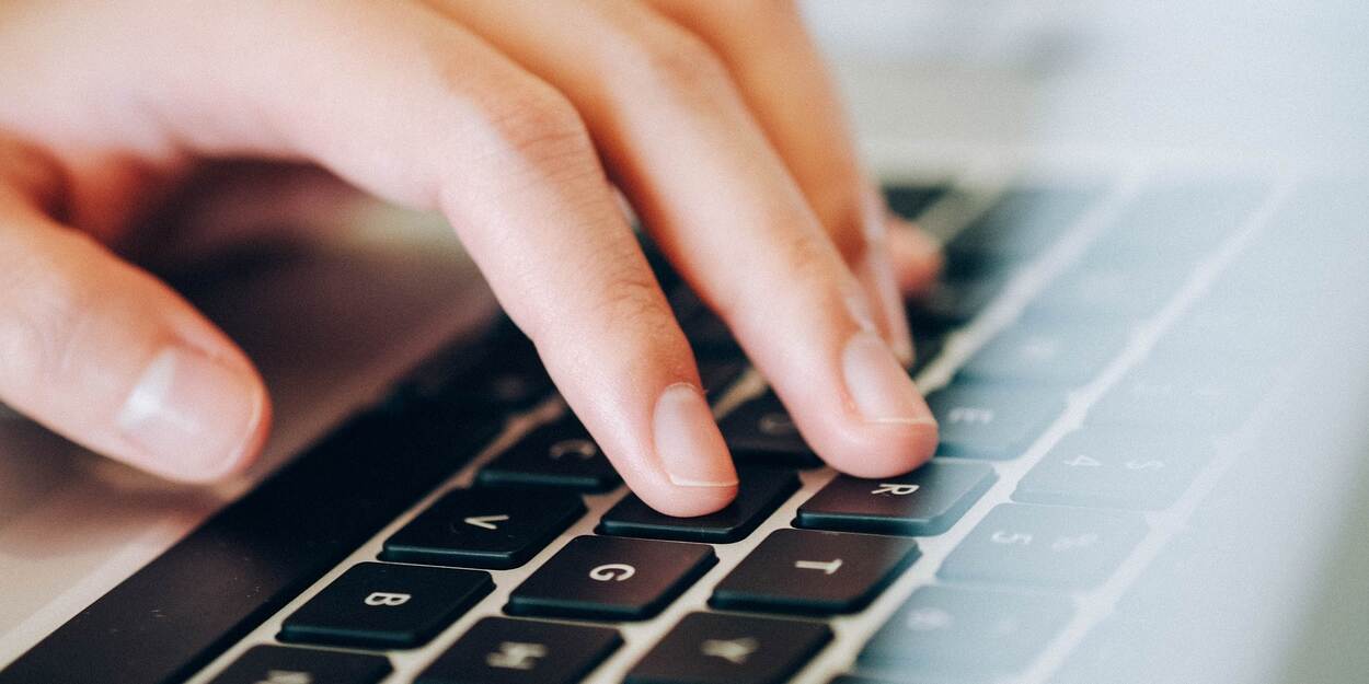 Hand op het toetsenbord van een laptop.
